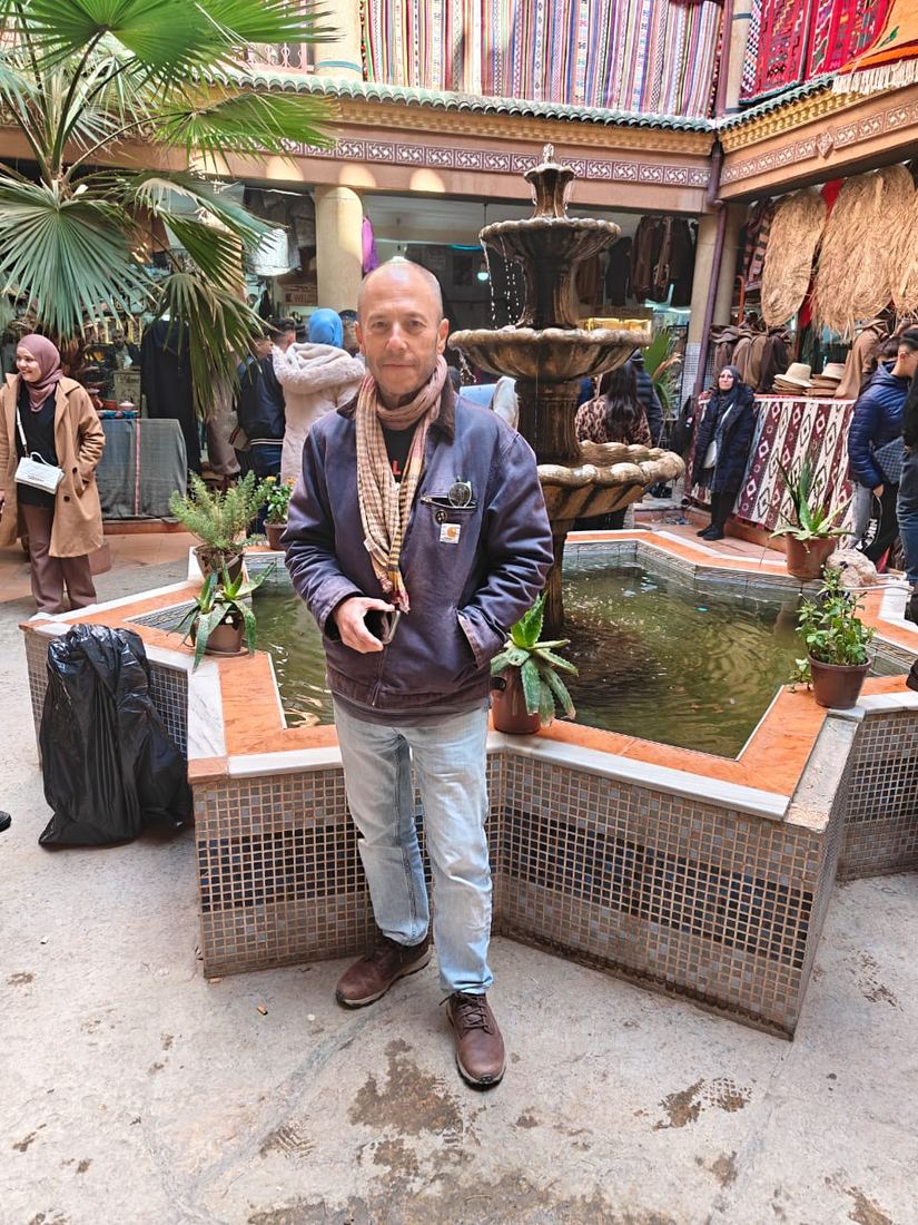 Un viaggiatore accanto a una fontana piastrellata nel cortile di un mercato artigiano
