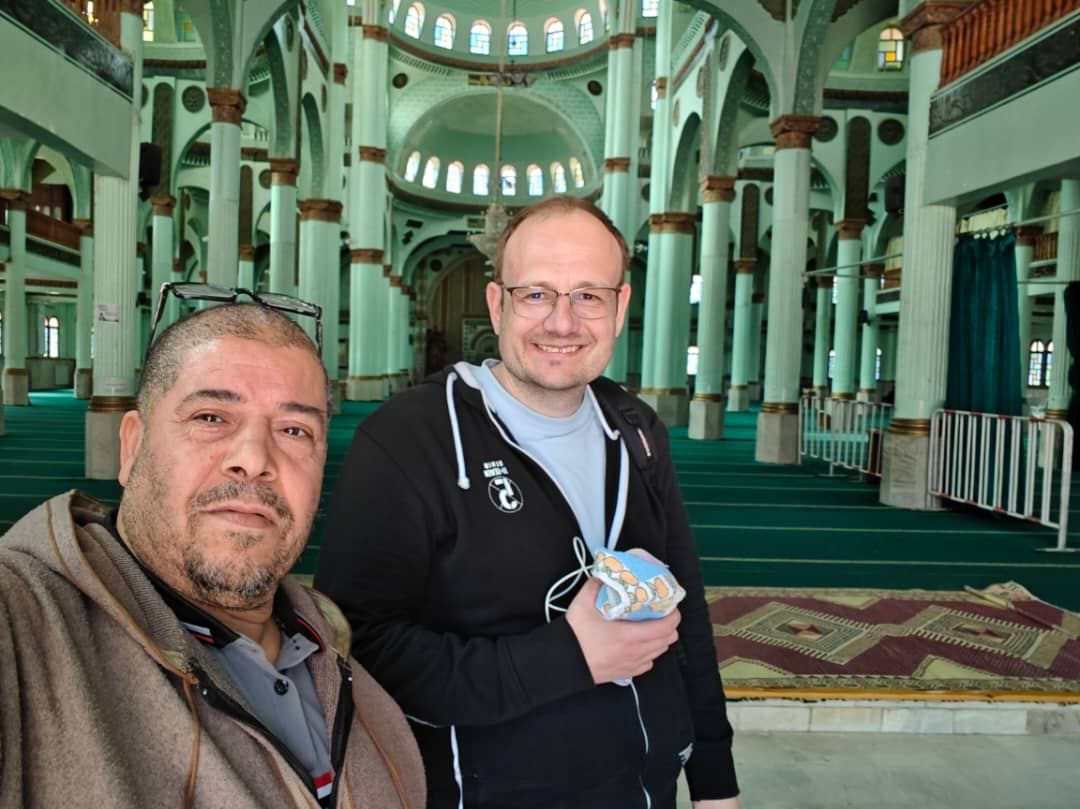 Una guida locale e un viaggiatore si scattano un selfie dentro una moschea verde chiaro con colonne