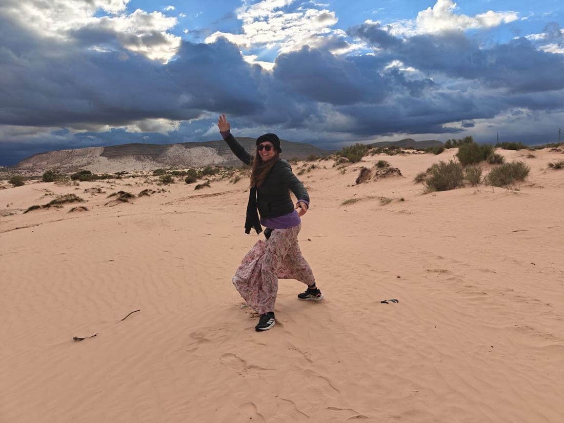Un viaggiatore balla sulle dune sotto un cielo carico di nuvole