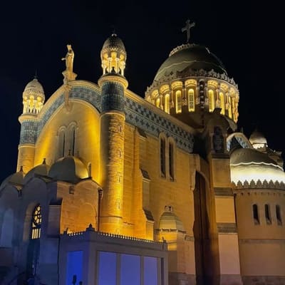 Notre-Dame d'Afrique floodlit at night above Algiers