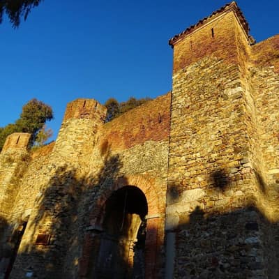 The stone walls and gateway of an old fortress in Béjaïa, lit by late sun