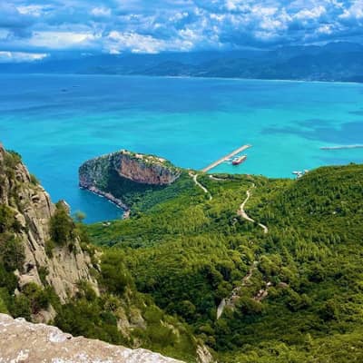 A forested headland curling into a turquoise bay near Béjaïa