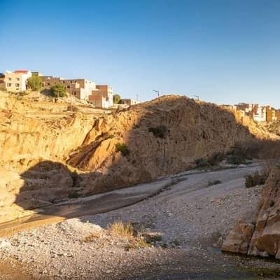 A rock spur rising above the dry riverbed of the oued at Bou Saâda