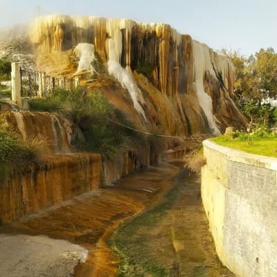 Mineral terraces where spring water cascades down a rock face at the oasis of Bou Saâda