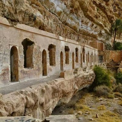 A row of openings cut into a sandstone cliff above a wadi