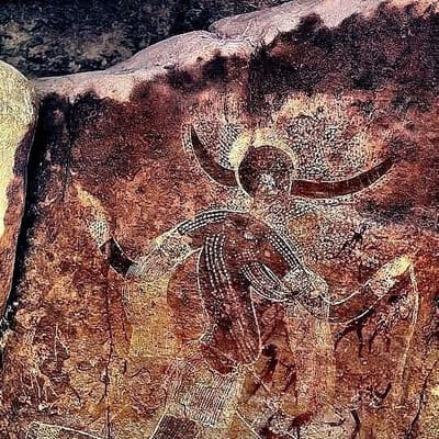 A prehistoric painting of a horned figure in dotted patterns in the Tassili n'Ajjer