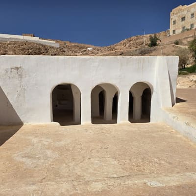 The whitewashed arcaded front of a M'Zab prayer hall, cut into the slope below the town