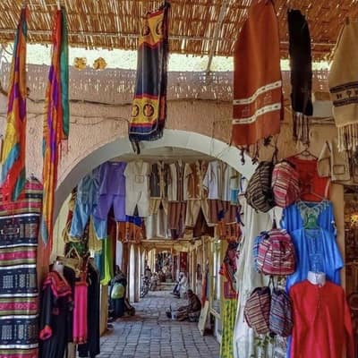 Textiles, bags and baskets hung along a covered market lane in Ghardaïa