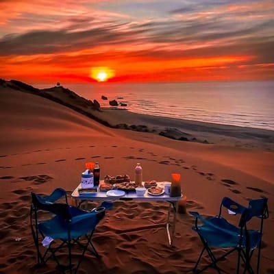 A table set for dinner on the sand at sunset by the sea near Mostaganem