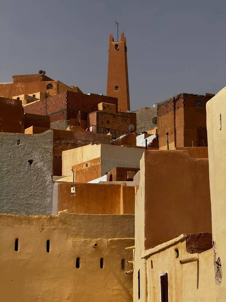Ochre and whitewashed rooftops of a M'Zab town stacked up towards its plain pyramid minaret