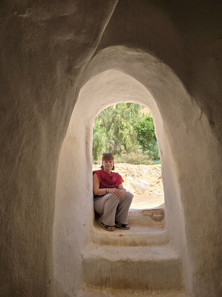 A traveller resting in the hand-moulded arched doorway of the Sidi Brahim mausoleum at El Atteuf
