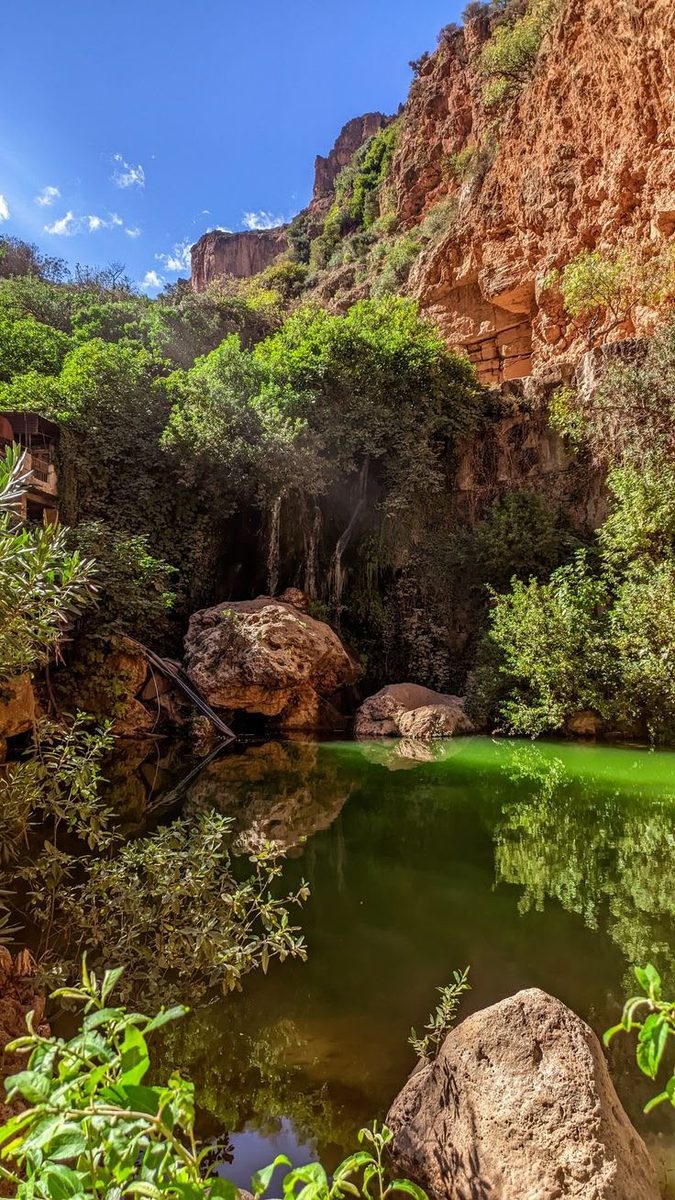A cascade falling into a green pool in the red gorge outside Tlemcen